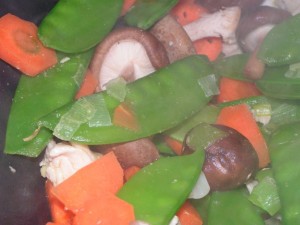 Dampfende Karotten, Zuckerschoten, Shiitake-Pilze und Pute im Wok